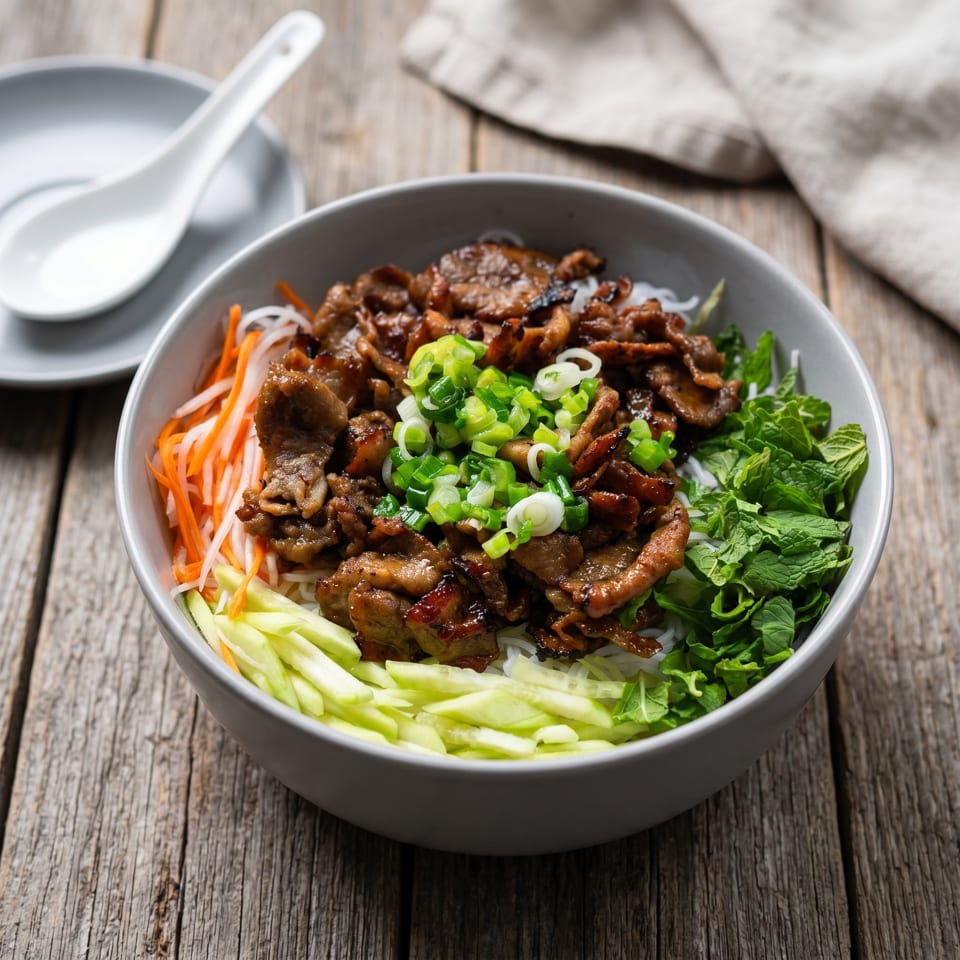 Vietnamese vermicelli noodle bowl with grilled pork, fresh mint, carrots, cucumbers, and scallions.